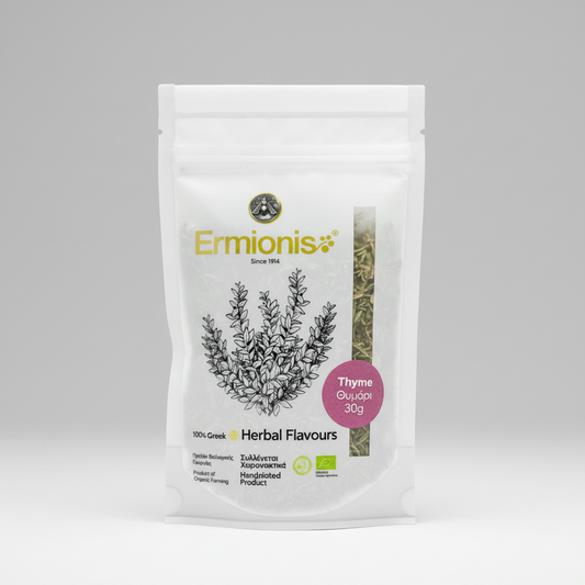A white stand-up pouch of Ermionis Thyme herbs, featuring a black line drawing of a thyme plant and a pink circular label, set against a neutral gray background.