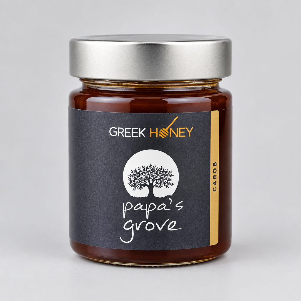 A closeup of a glass jar of Greek Honey from Papa's Grove, filled with dark amber honey and featuring a black label with a white tree logo and a silver metal lid, set against a neutral gray background.